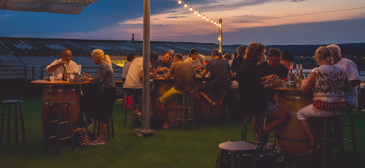 Terrasse du restaurant remplie de clients avec le coucher de soleil en arrière plan